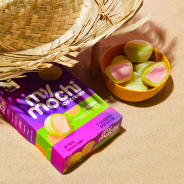 Image of guava My/Mochi box next to yellow bowl full of guava My/Mochi ball underneath straw hat on a sandy beach