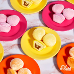 Image of bright colored plates with  My/Mochi balls; two yellow plates with yellow mochi balls, two hot pink plates with pink mochi balls, and two orange plates with orange mochi balls
